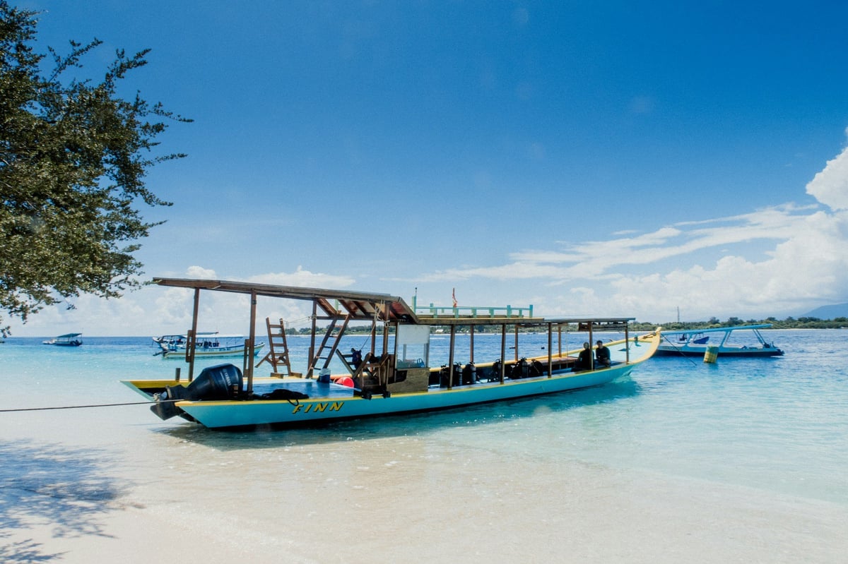 A wooden boat in clear shallow water off a Gili island beach