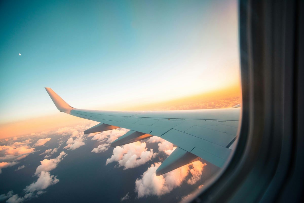 An airplane wing at sunset seen through a cabin window