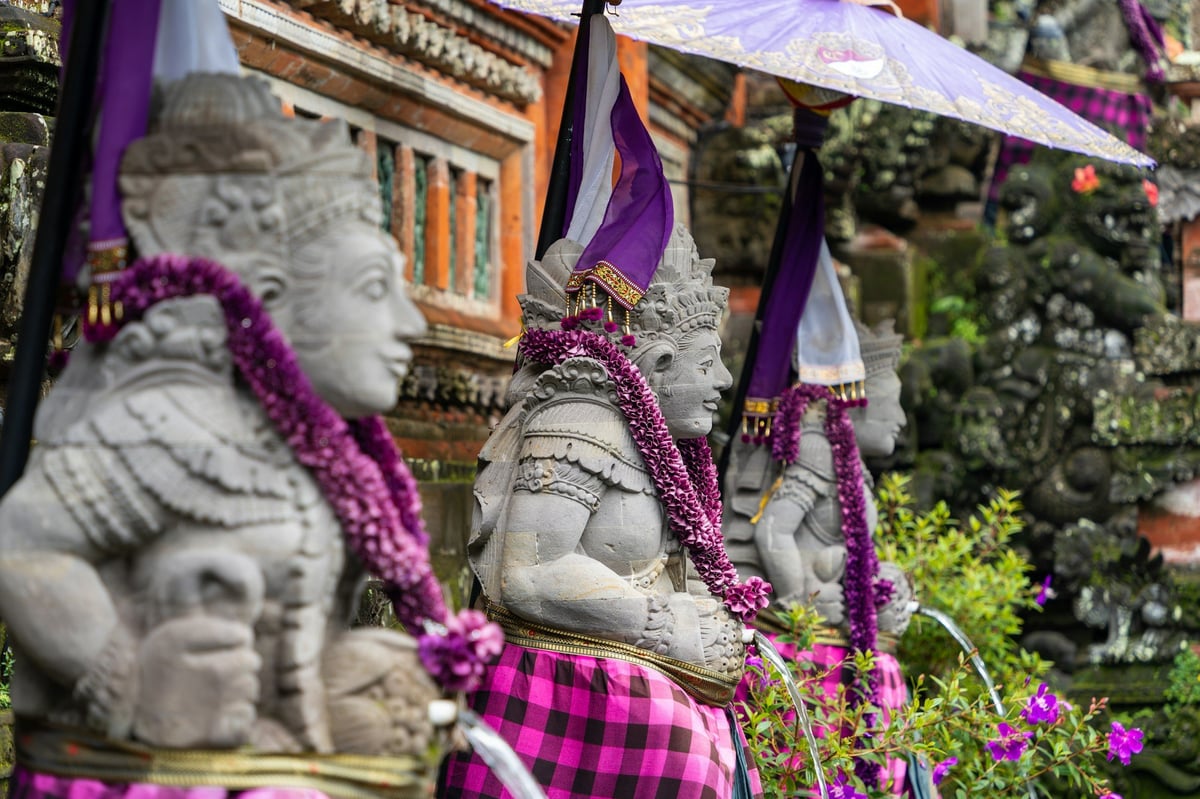 Stone guardian statues draped with flower garlands at a Balinese temple