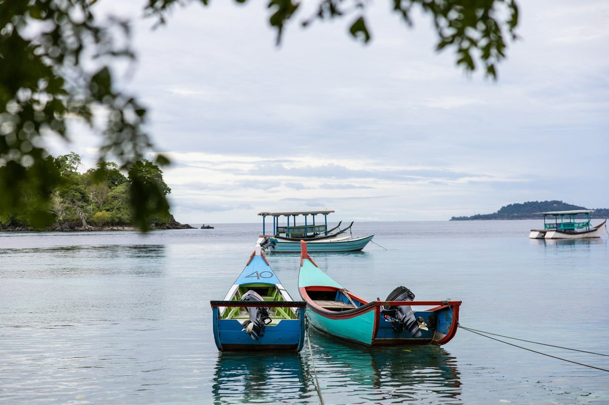 Small boats moored in a calm bay with islands beyond