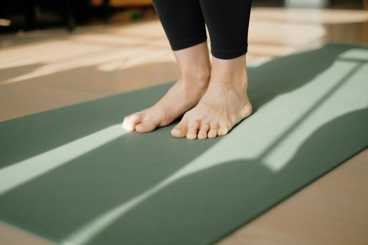 Bare feet on a yoga mat in a sunlit room