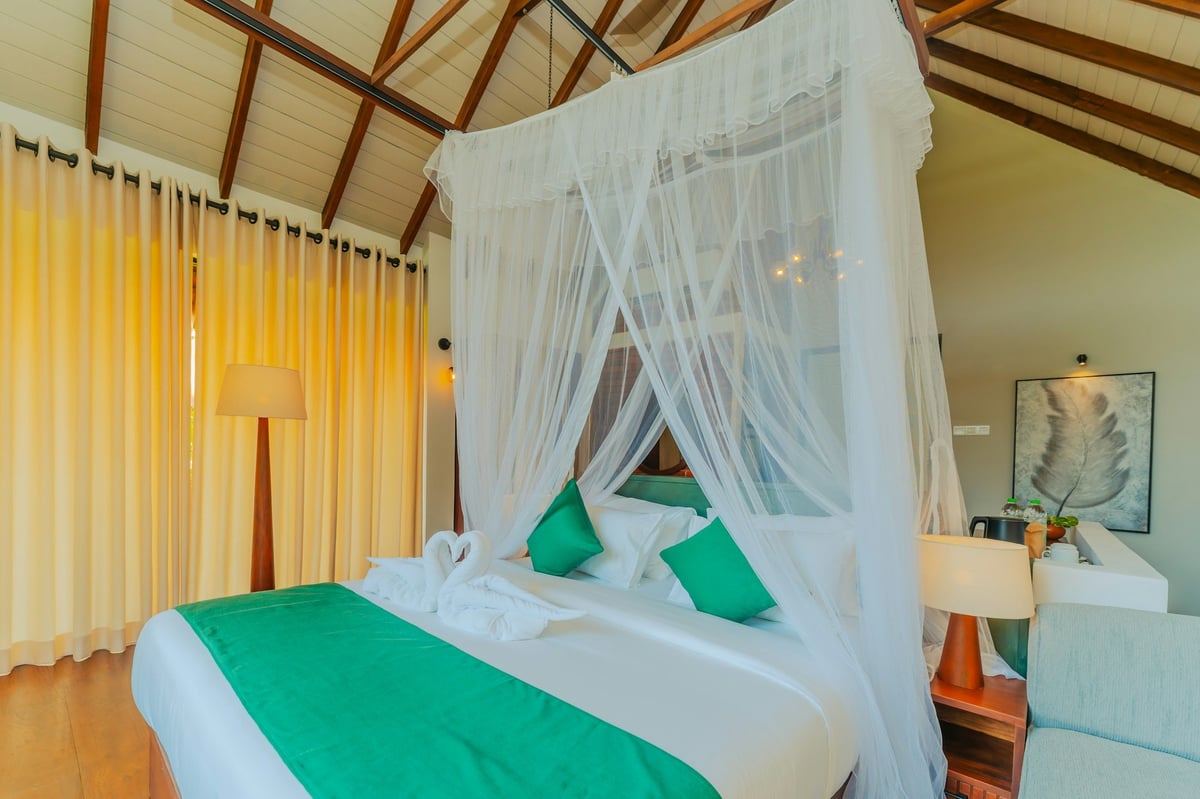 A bed with a mosquito net in a tropical bungalow