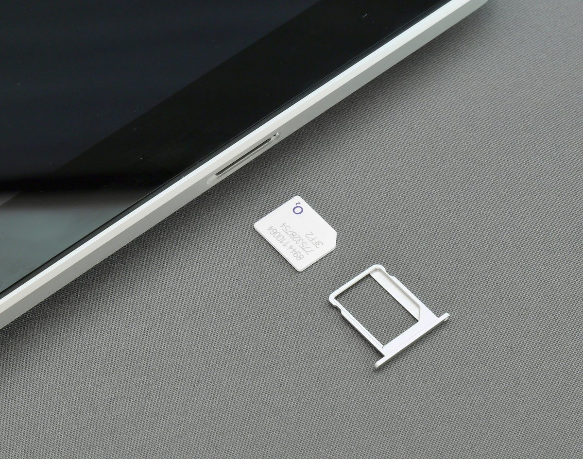 A SIM card and SIM tray beside a smartphone