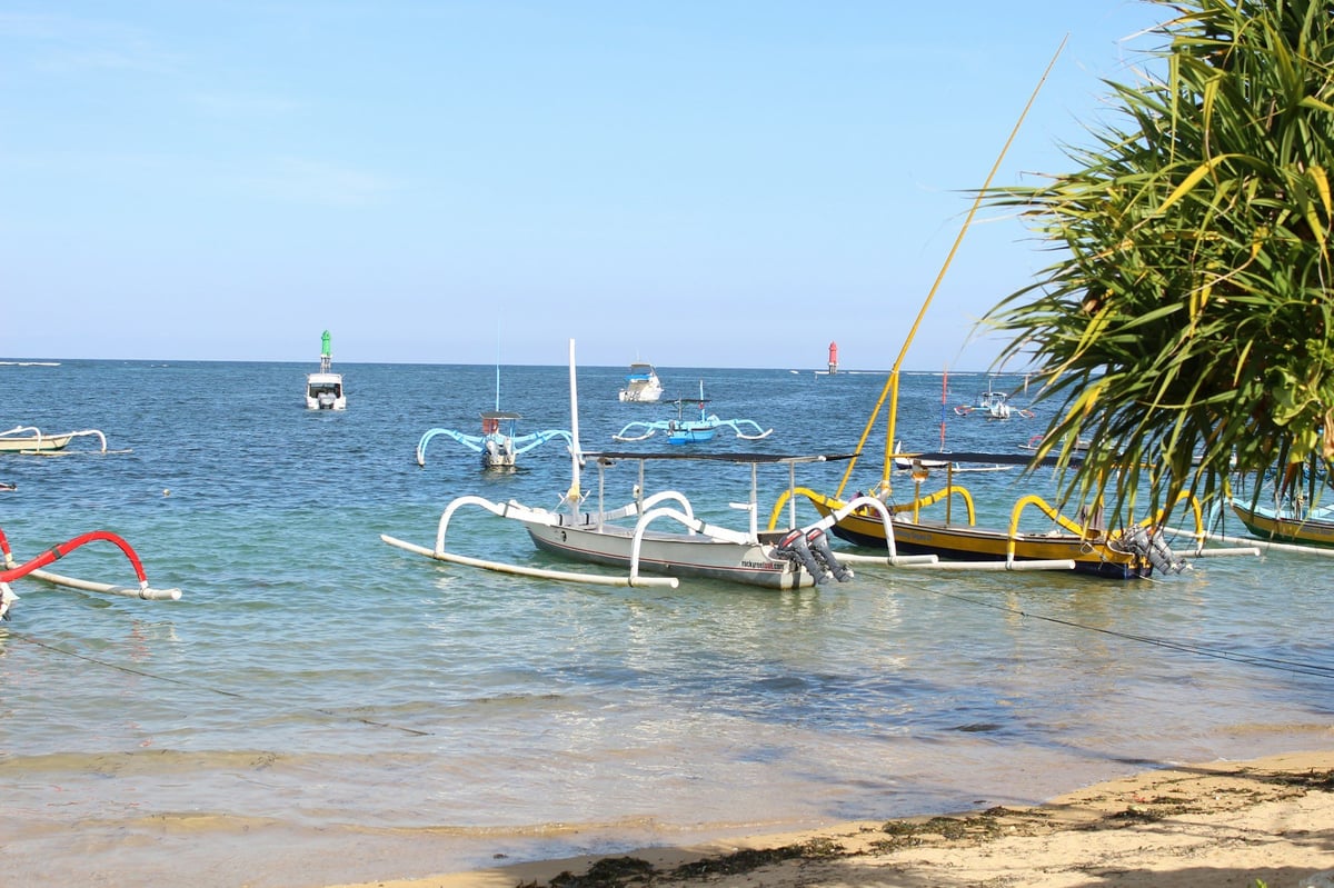 Outrigger boats moored in shallow water off a beach in Bali