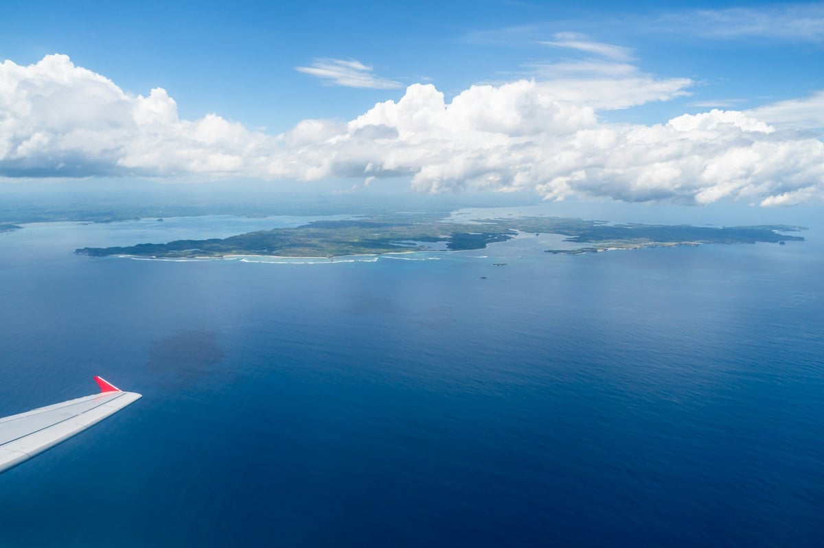An island seen from an airplane window over blue sea