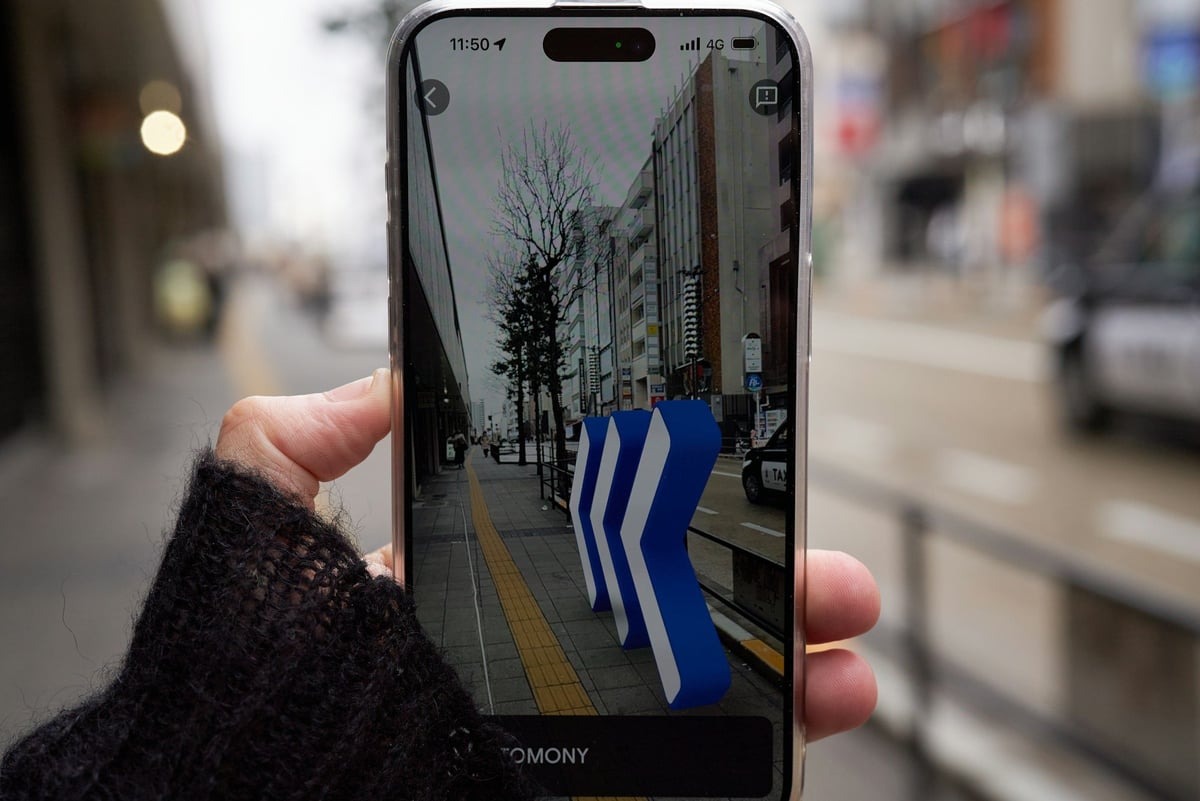A hand holding a smartphone on a city street