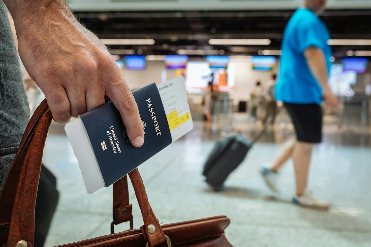 A traveler holding a US passport and boarding pass in an airport terminal