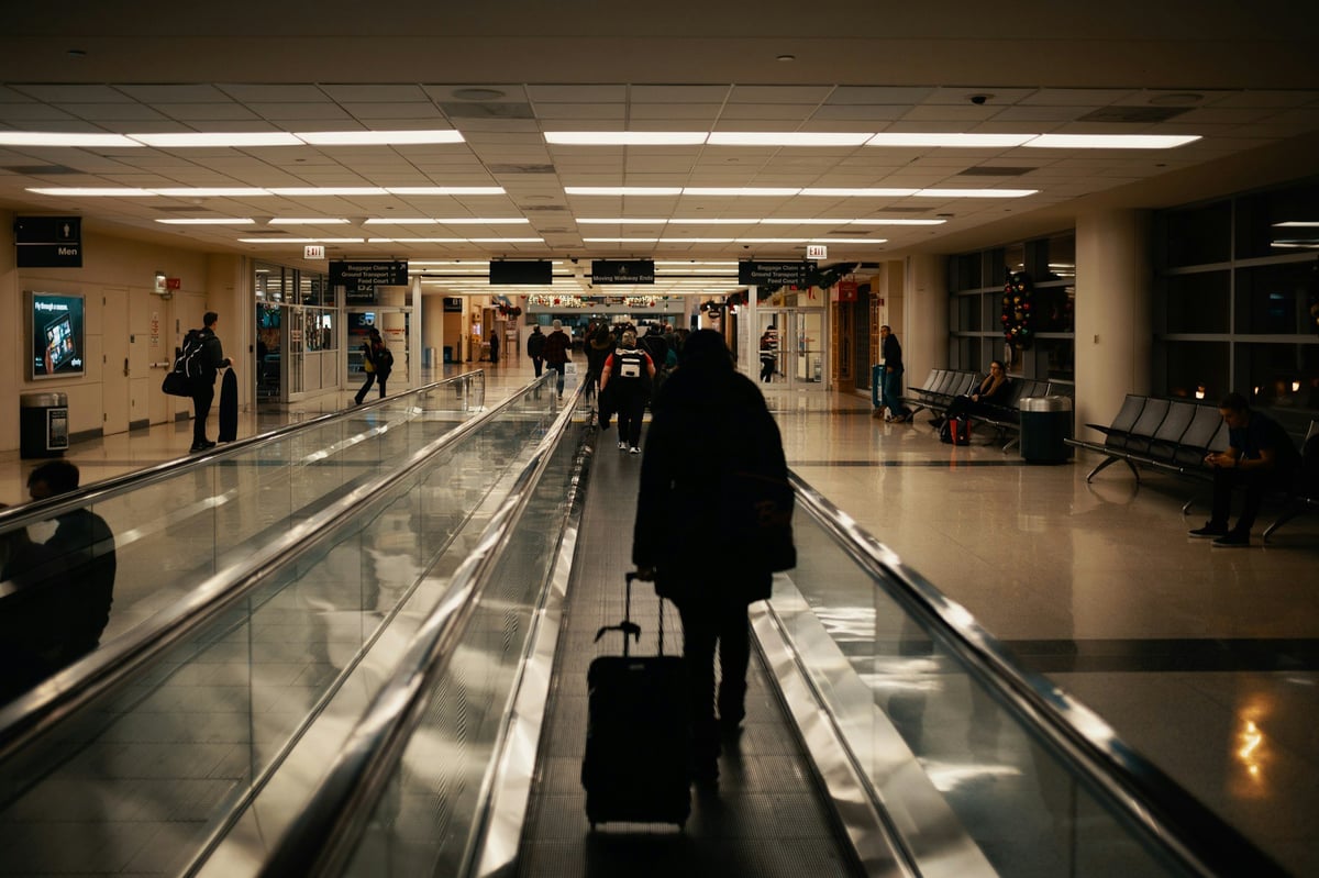 A traveler with a suitcase on an airport walkway