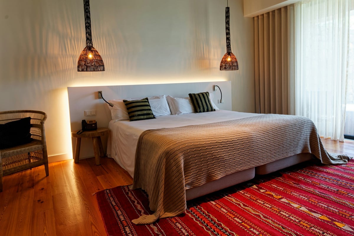 A hotel bedroom with a wide bed and soft lighting