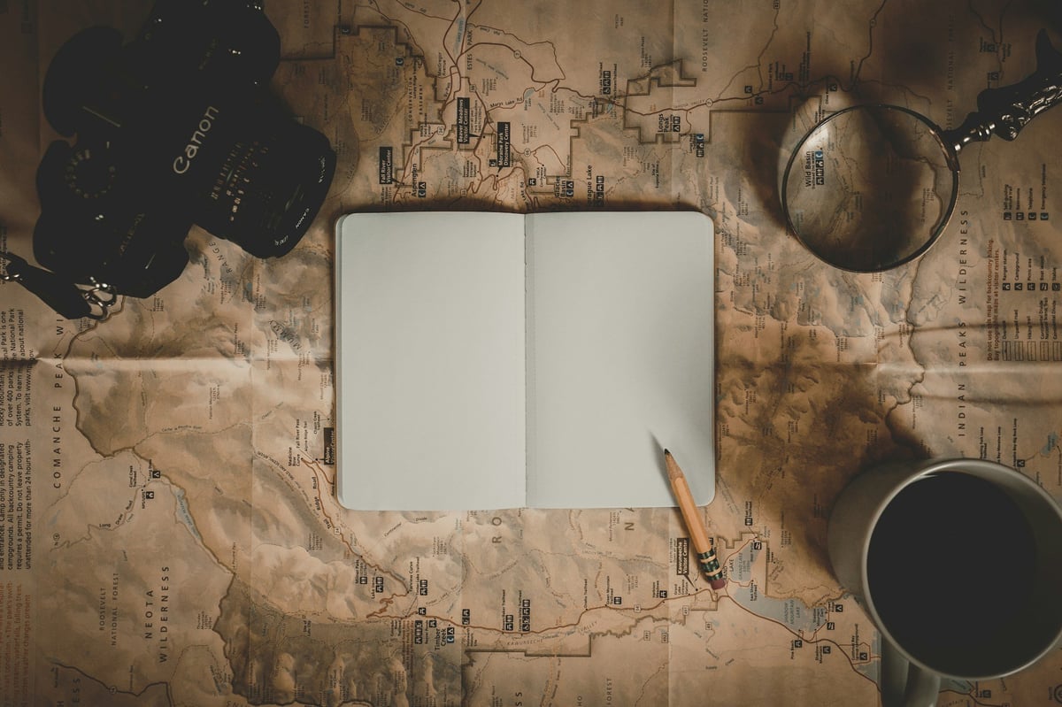 A notebook and coffee on an old map