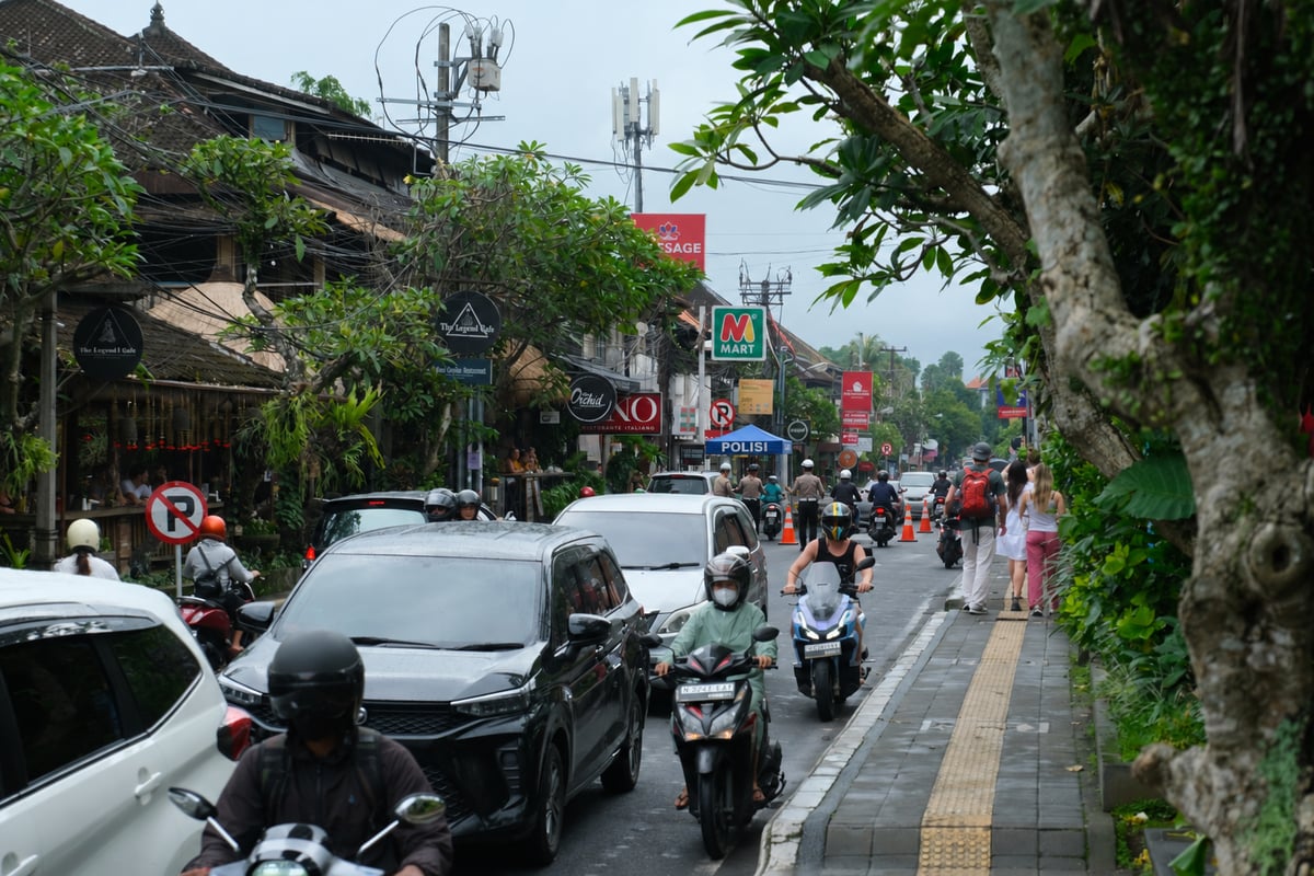 A roadside police checkpoint in Indonesia seen from a distance, officers standing beside the road as motorbikes pass