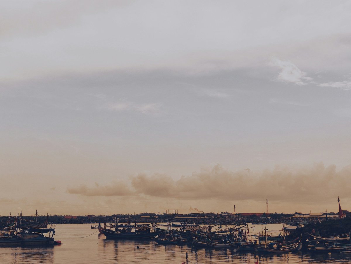 Boats in a harbor under a cloudy evening sky