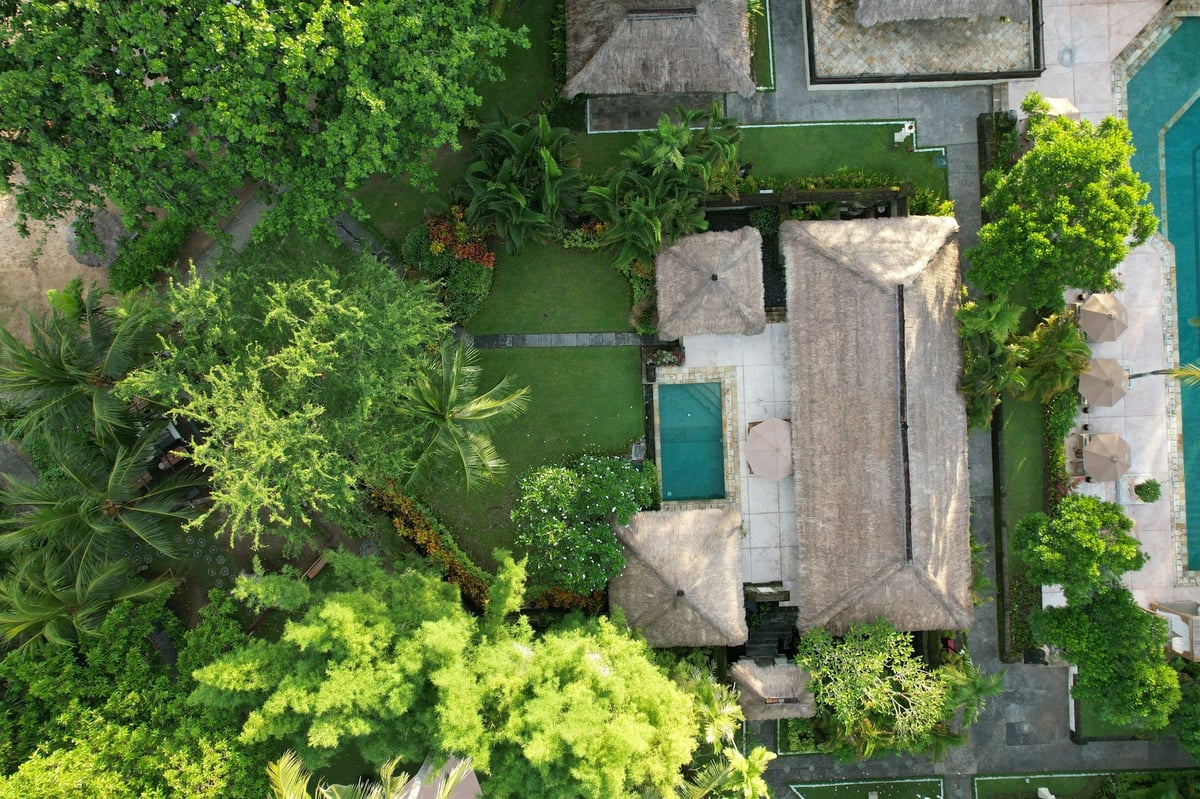 A villa and its pool seen from above among trees in Bali
