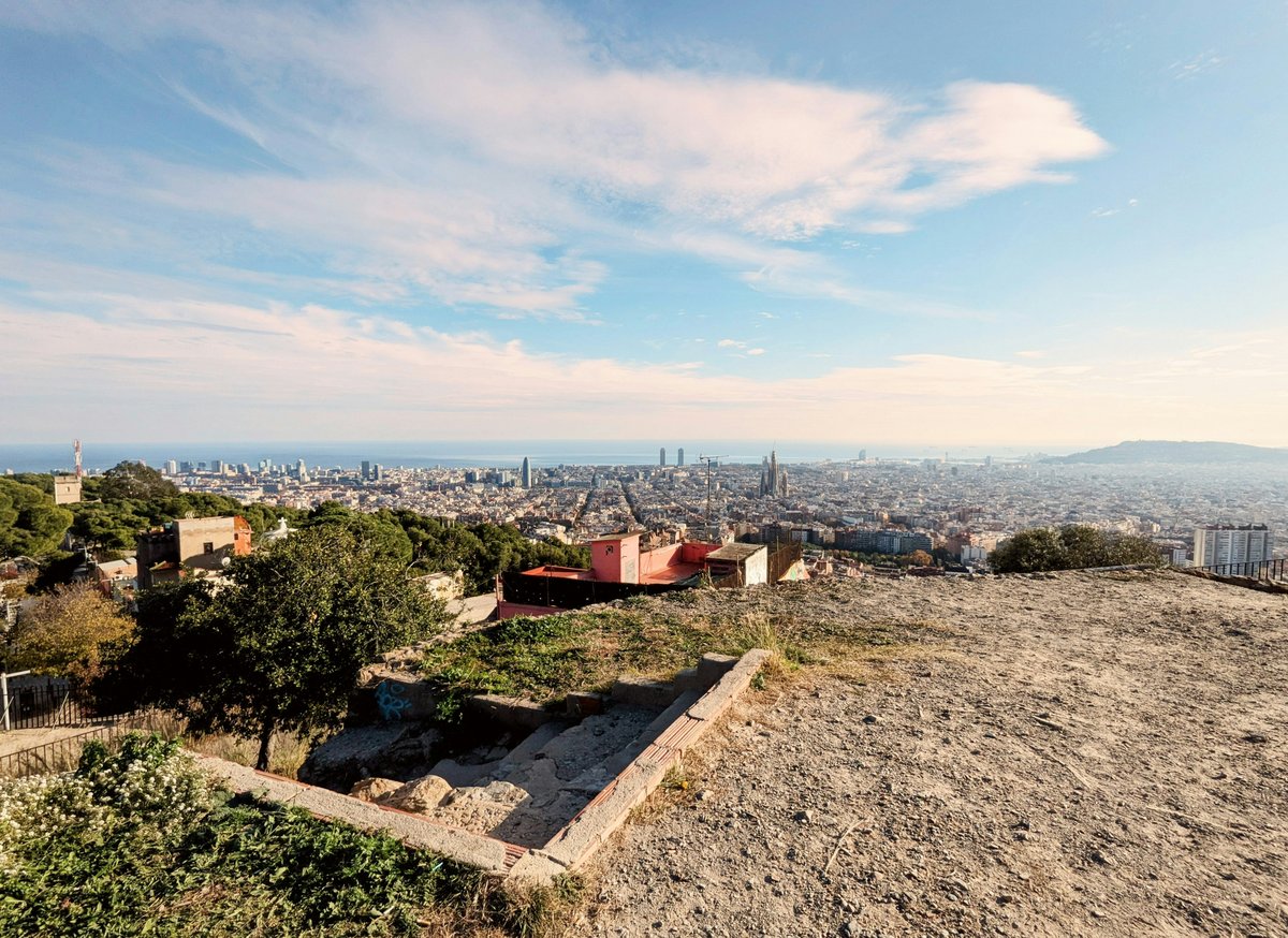 A sweeping Barcelona panorama at golden hour — the city grid, Sagrada Família, and the sea