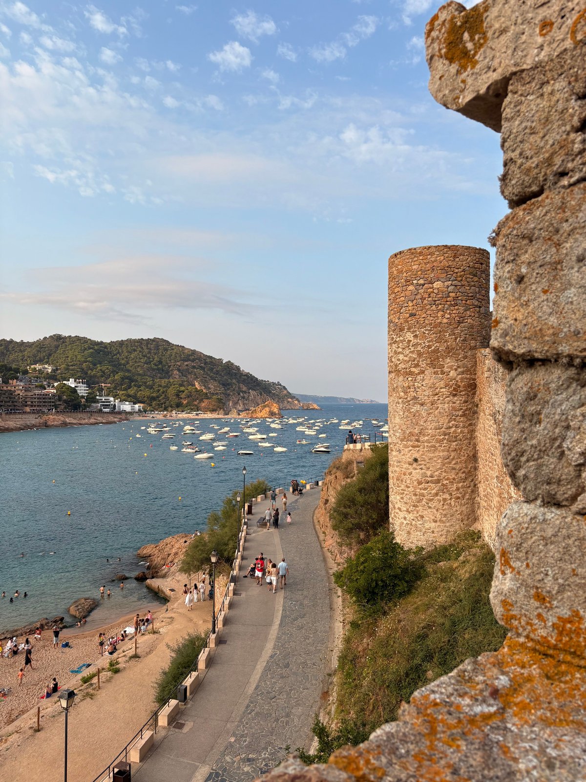 A classic Costa Brava cove — turquoise water, whitewashed village, pine cliffs (e.g. Calella de Palafrugell or Tossa de Mar)