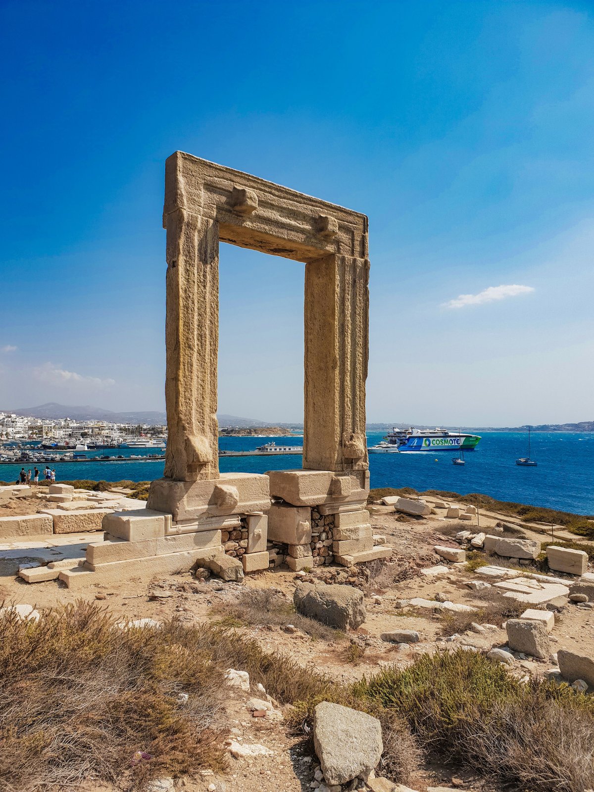 The Portara marble gateway at sunset on Naxos, with the harbor behind it