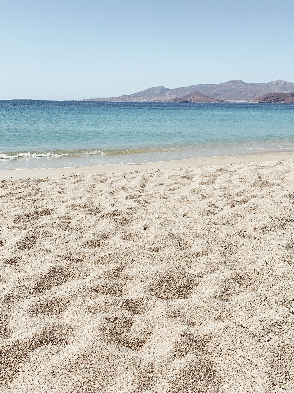 A relaxed Cycladic island scene — quiet beach or whitewashed village lane