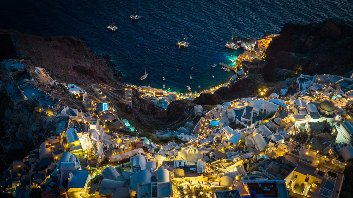 Oia at golden hour, blue domes and whitewashed houses on the caldera