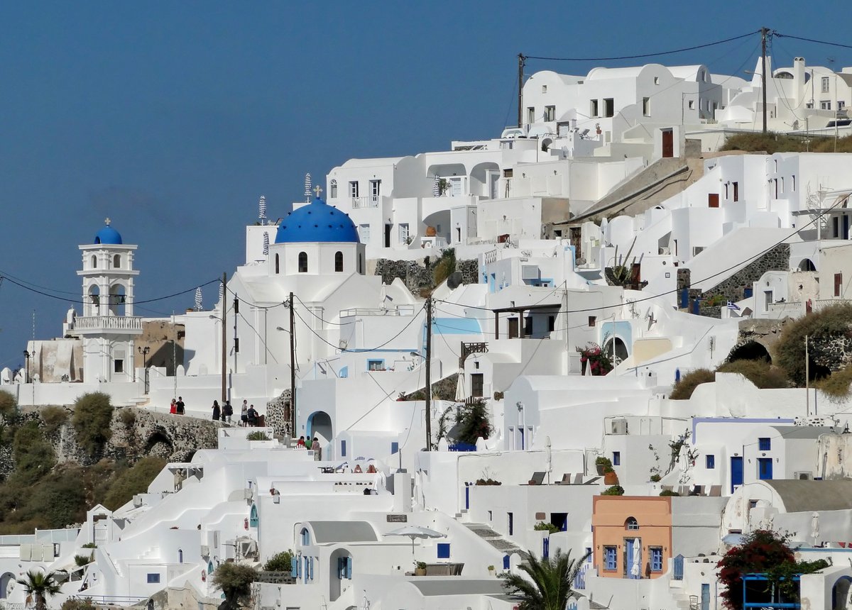 Whitewashed caldera-edge hotels cascading down the cliff at Imerovigli or Fira
