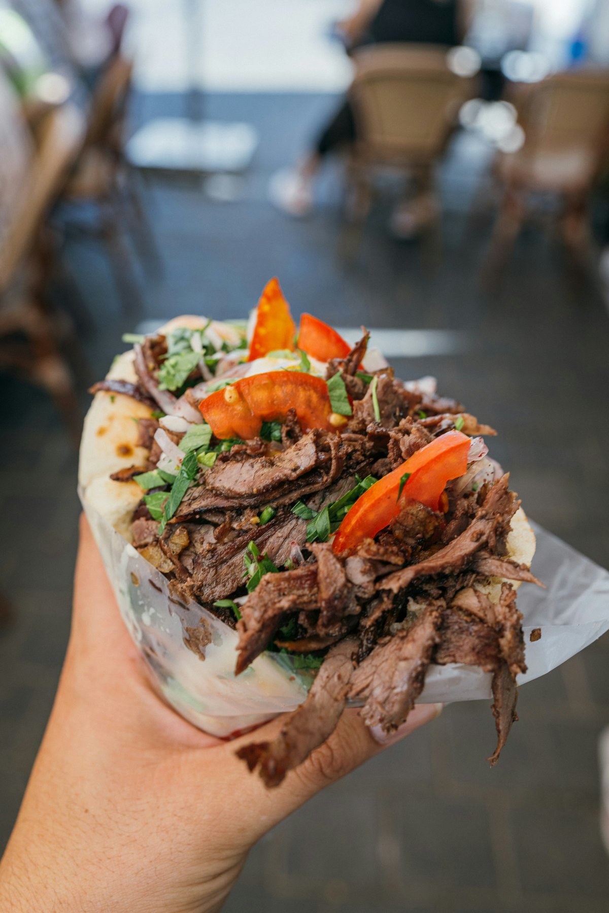 A freshly wrapped Greek gyros/souvlaki being served at a busy spot