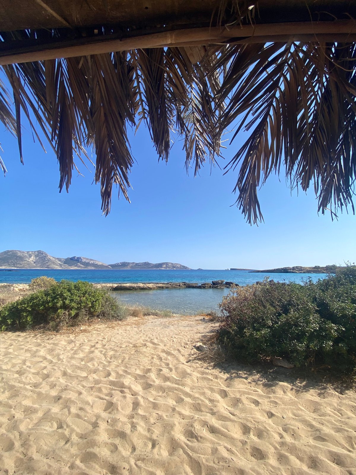 A calm, shallow, sandy Greek beach with families and gentle turquoise water