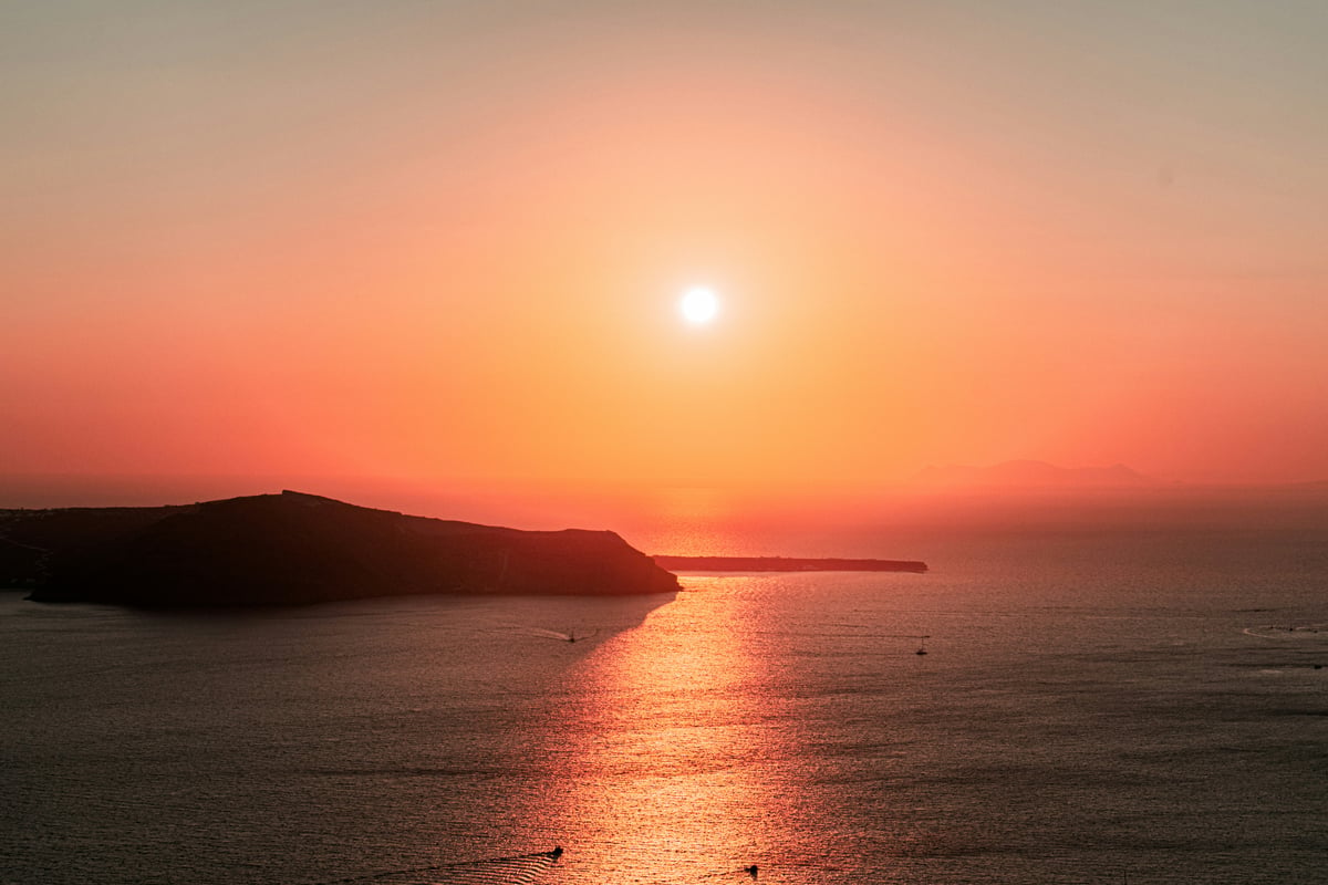 The Oia sunset over the caldera, golden light on white buildings