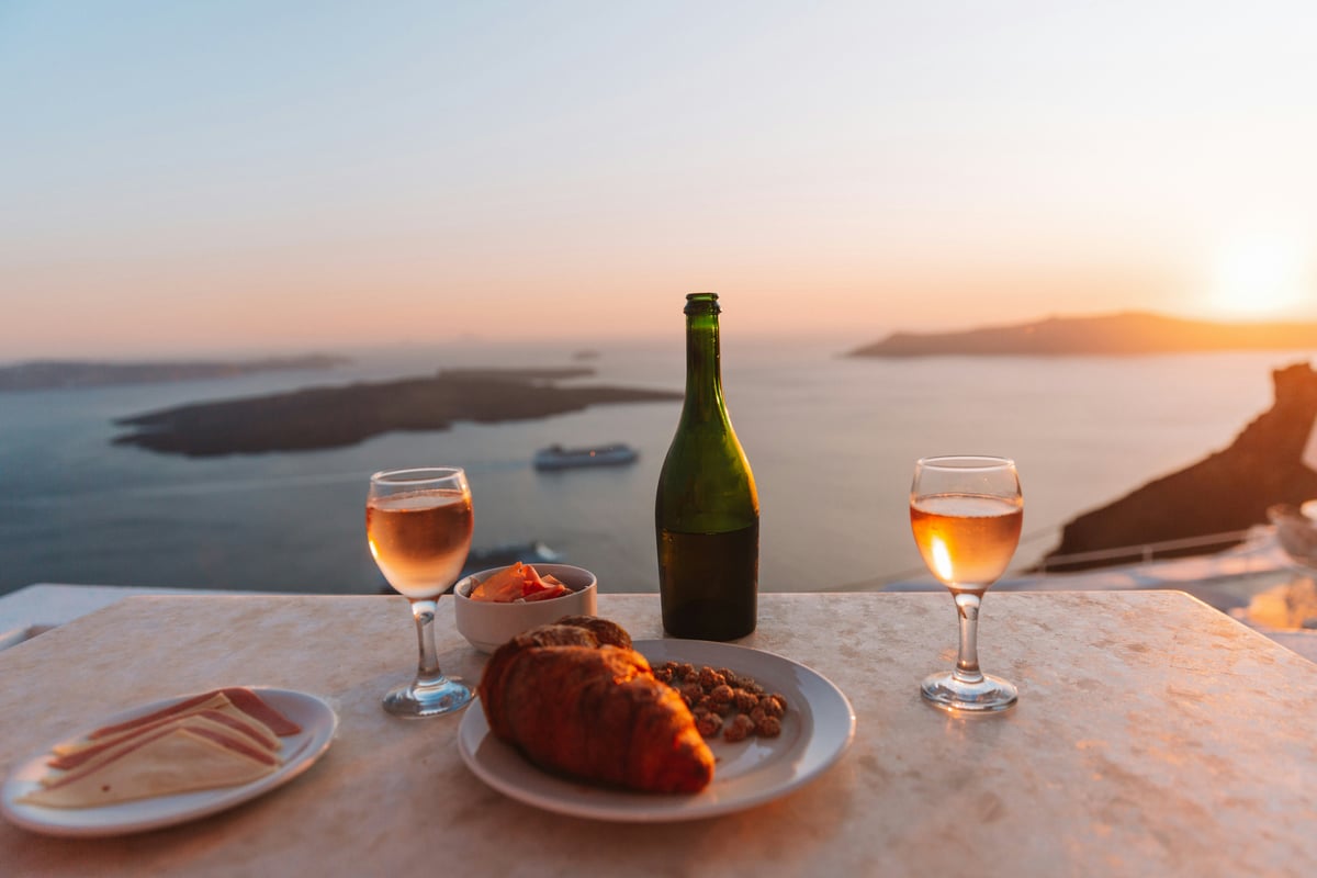 A Santorini winery terrace with caldera views and glasses of white wine