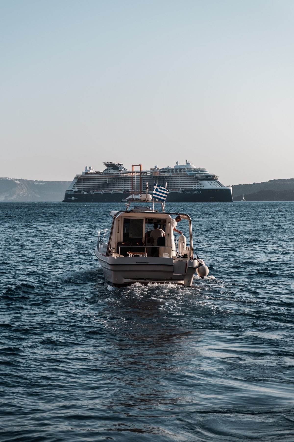 A ferry crossing between two Cycladic islands, town on the horizon