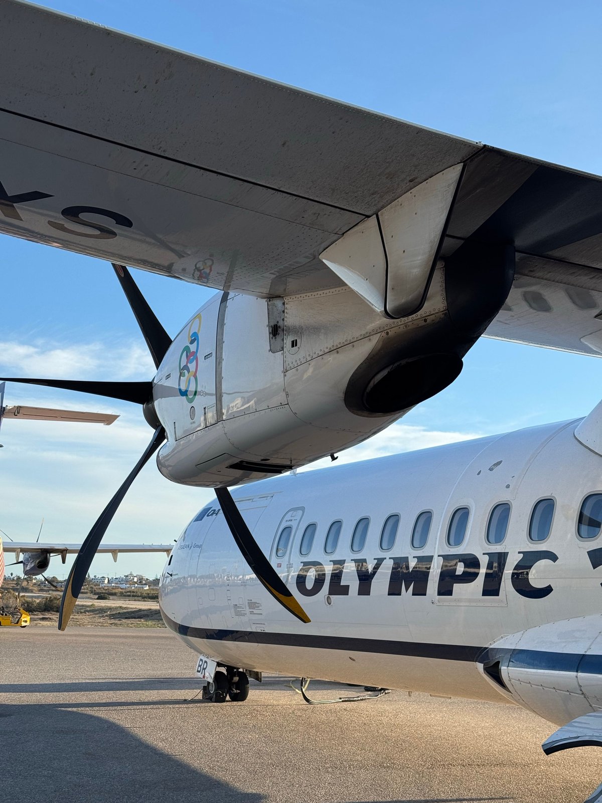A small plane on the tarmac at a Greek island airport with sea views