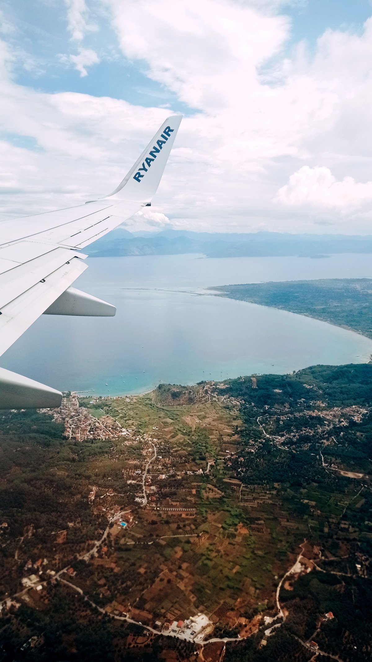 An aerial view of a Greek island from a plane window, blue sea below