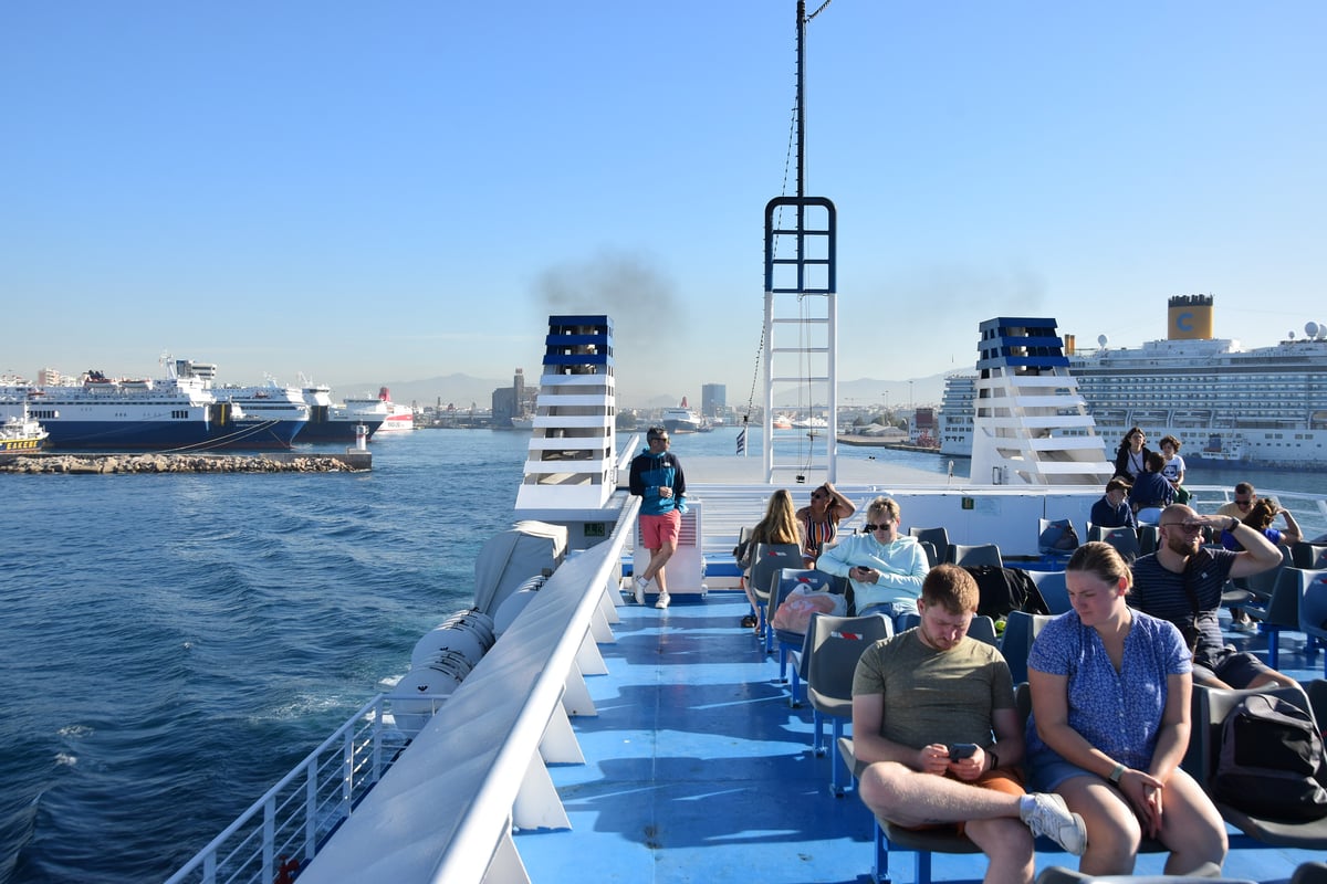 A ferry deck with passengers enjoying open-air views of the Aegean