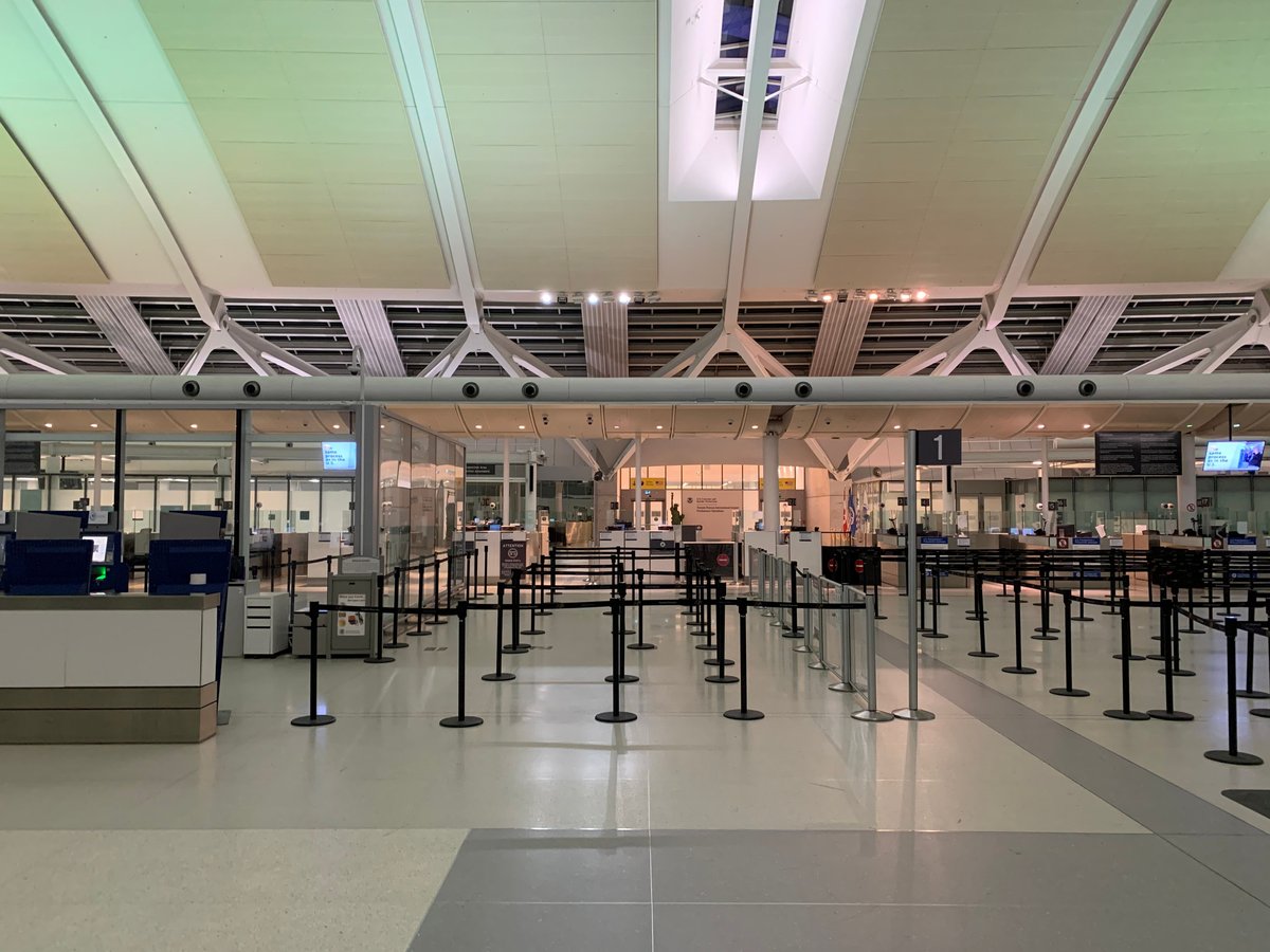 A modern airport arrivals hall or border control area (no identifiable faces)