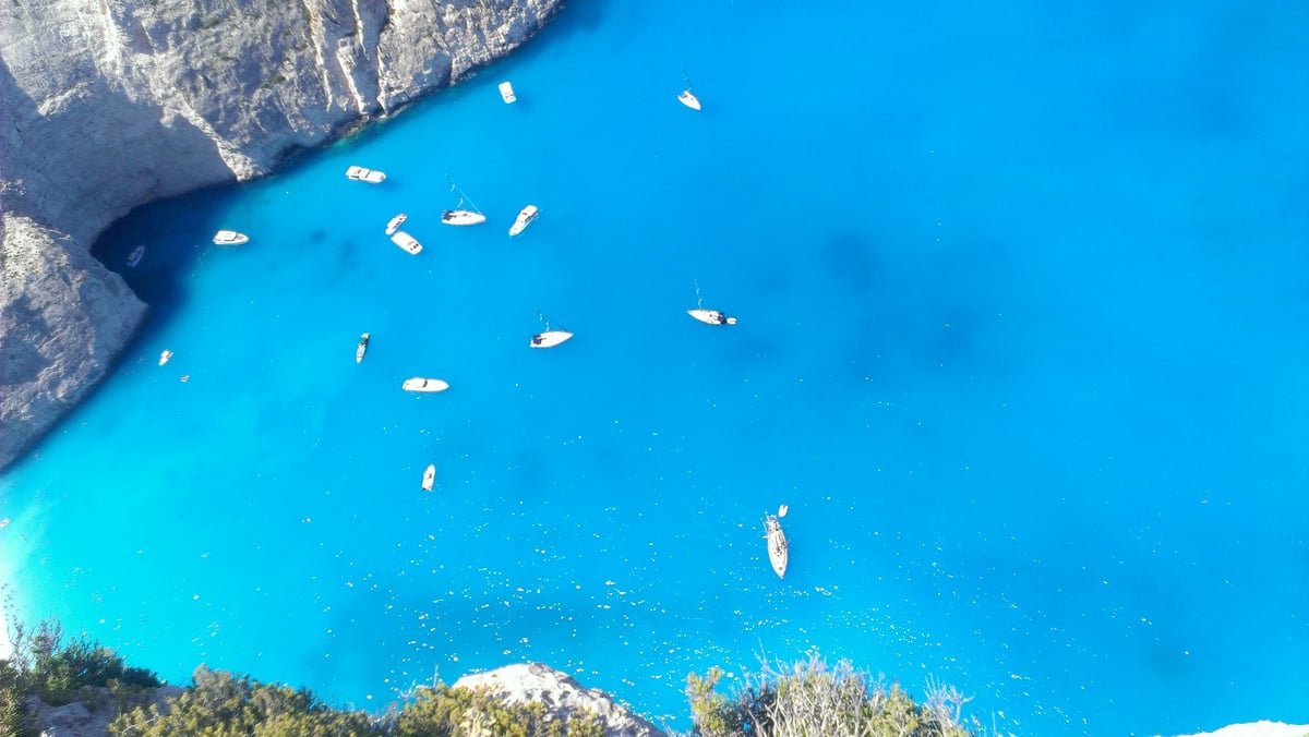 A quiet Cycladic beach with a couple walking, turquoise water, few people