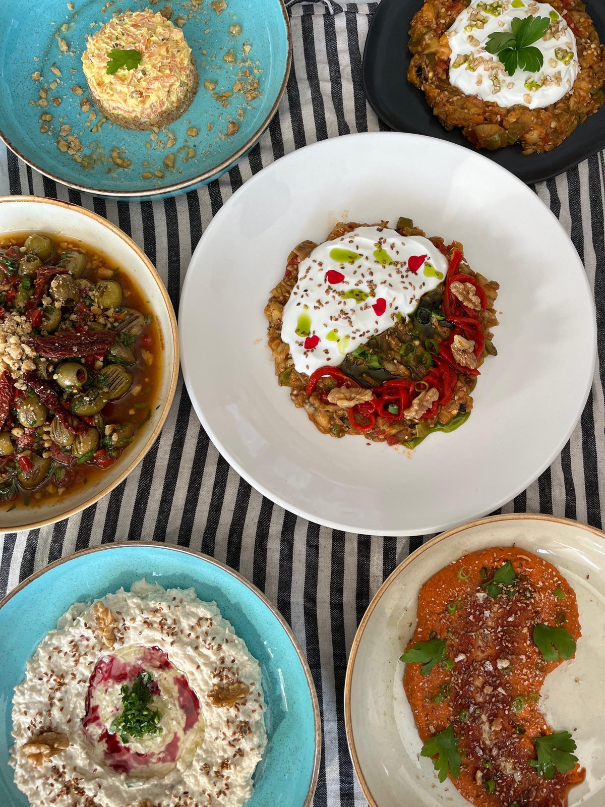 A taverna table spread with multiple Greek mezze dishes to share