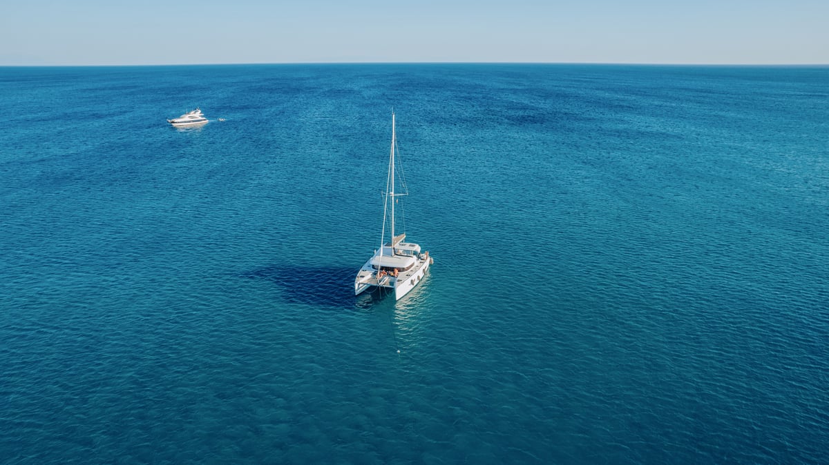 A large conventional ferry and a fast catamaran side by side in a Cycladic port