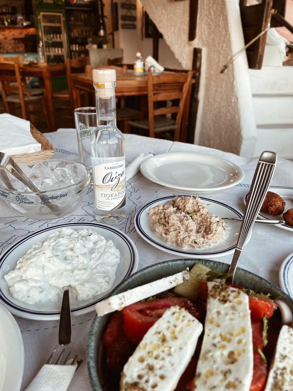 A shared taverna meal in progress, plates and glasses on a rustic table
