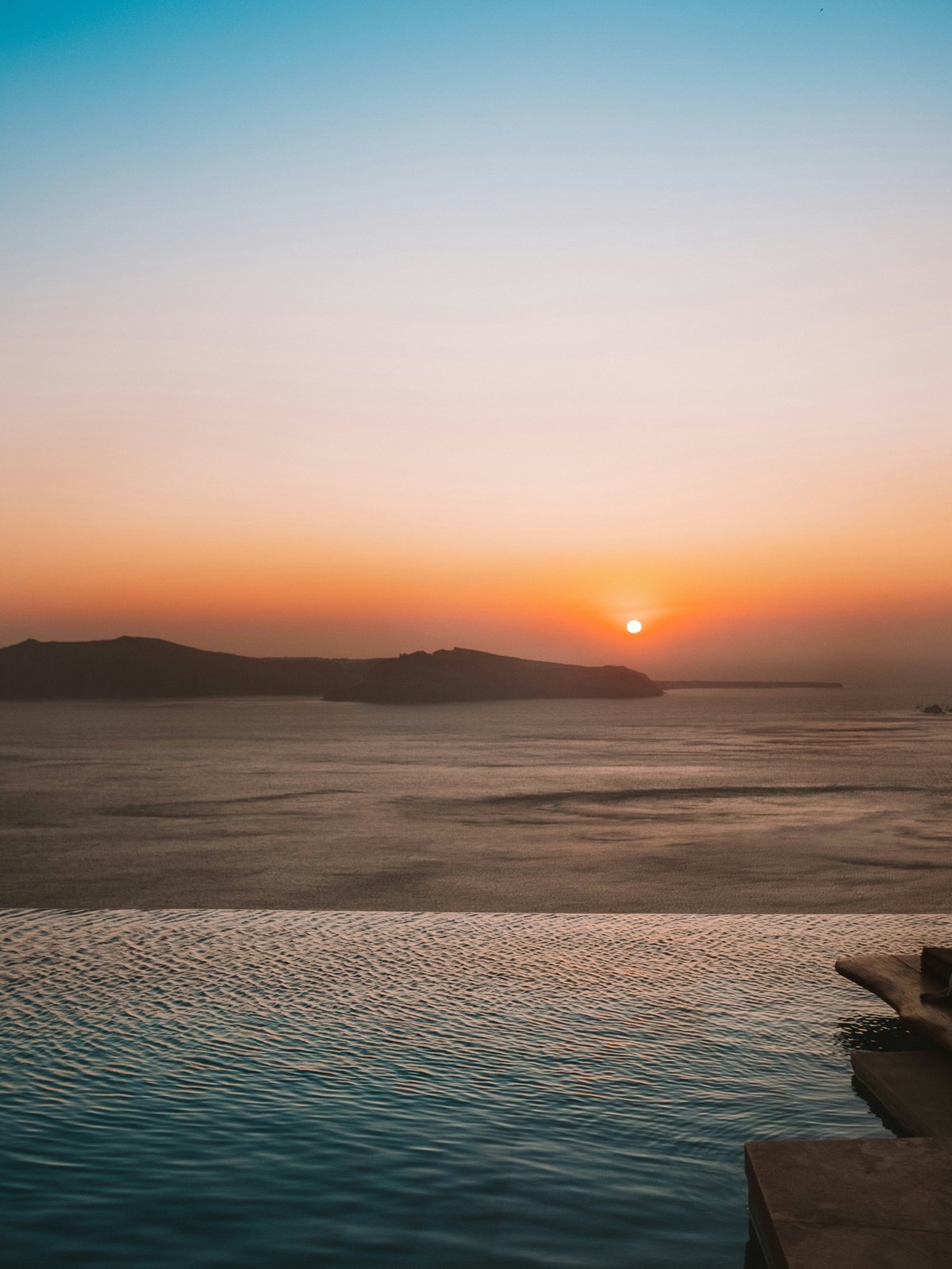 A Santorini caldera cave suite with a private infinity plunge pool at golden hour