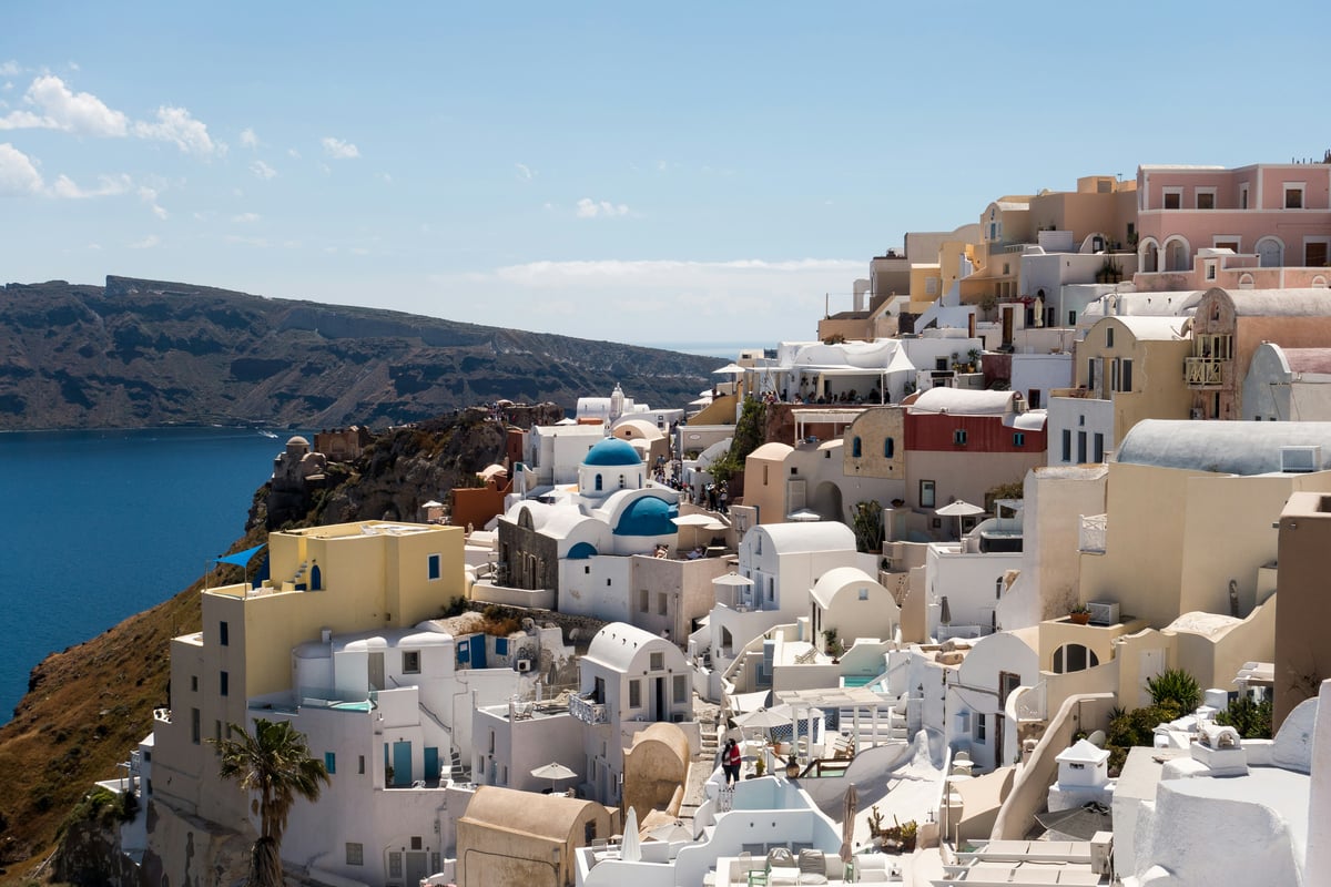 Classic Santorini caldera view — white buildings and blue domes above the deep blue sea