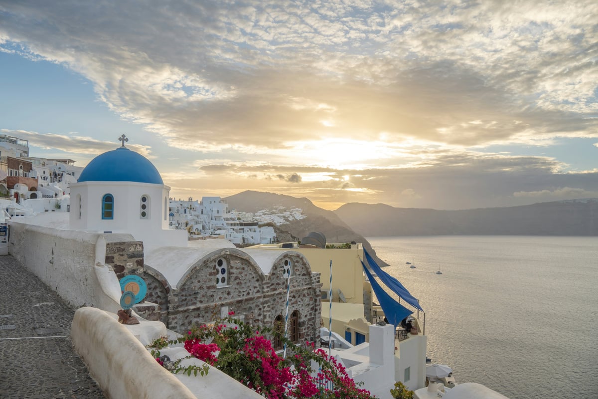 Oia village at golden hour, blue domes and whitewashed houses on the cliff