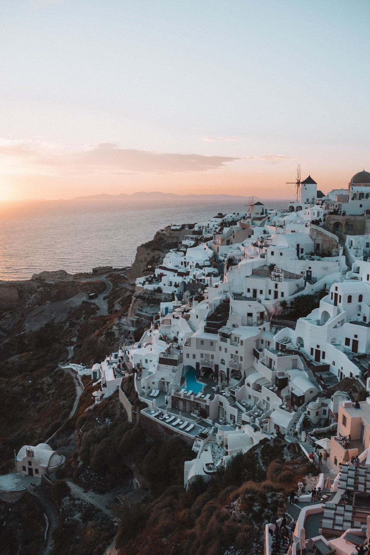 The sun setting over the Santorini caldera, golden light on Oia's white buildings
