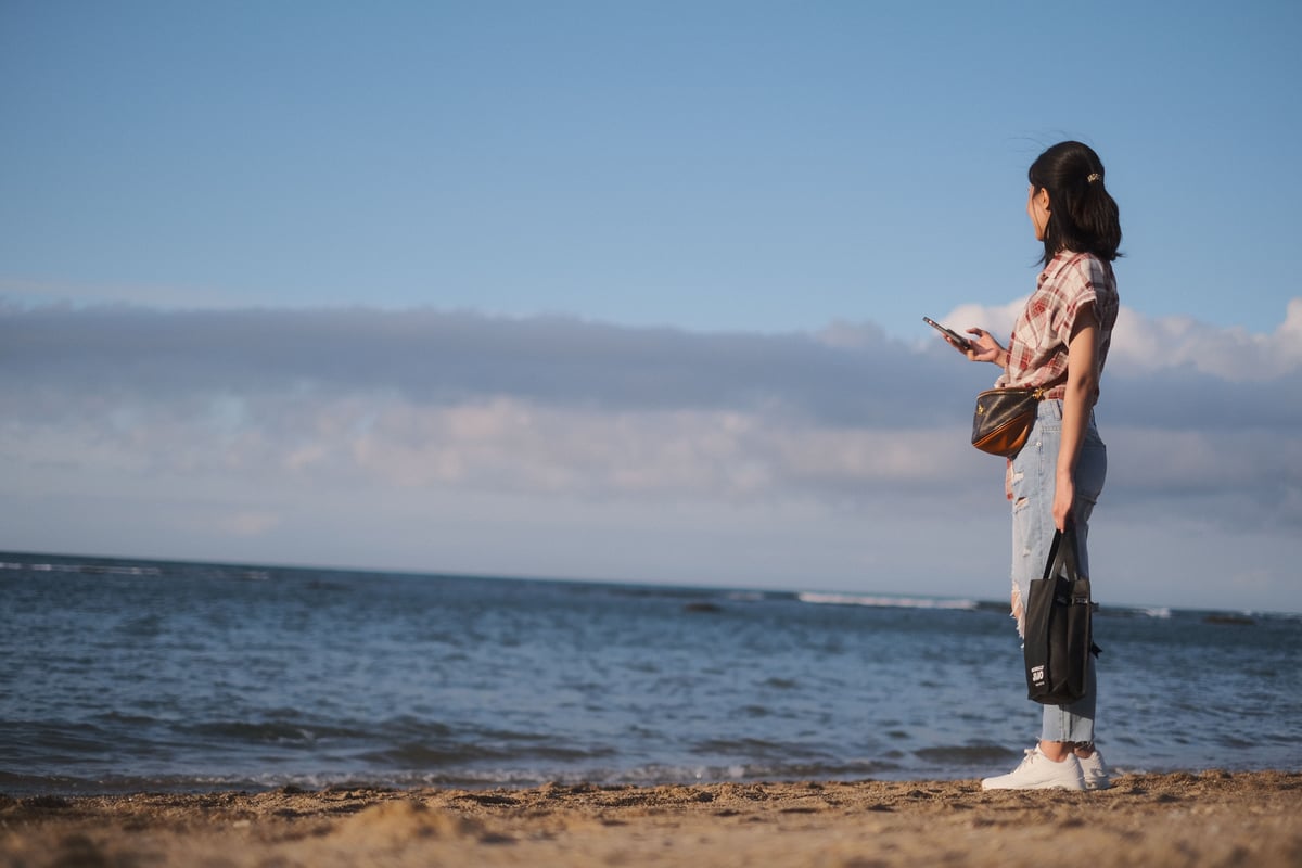 A traveler using a smartphone with a scenic Greek backdrop