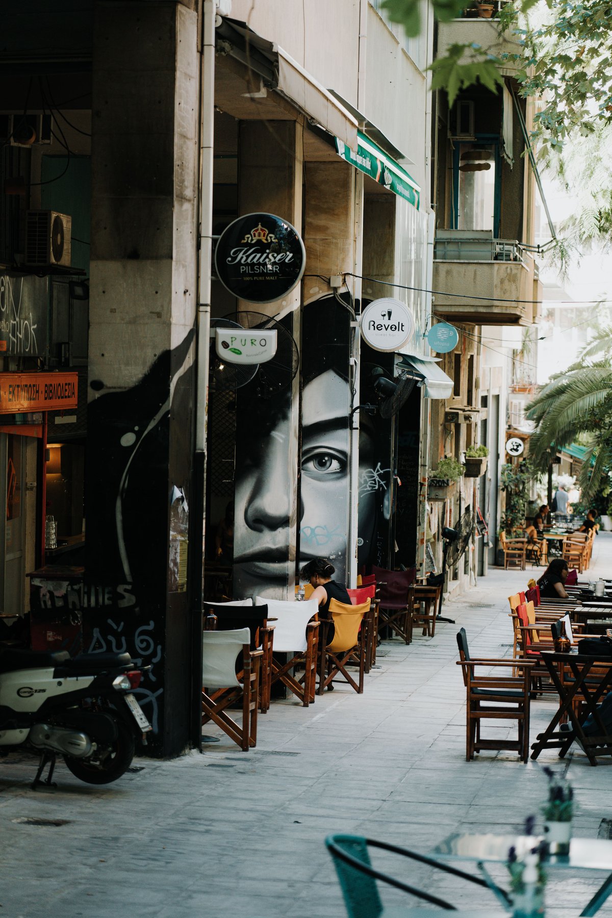 A quiet café-lined street in Koukaki or Kolonaki, locals at outdoor tables