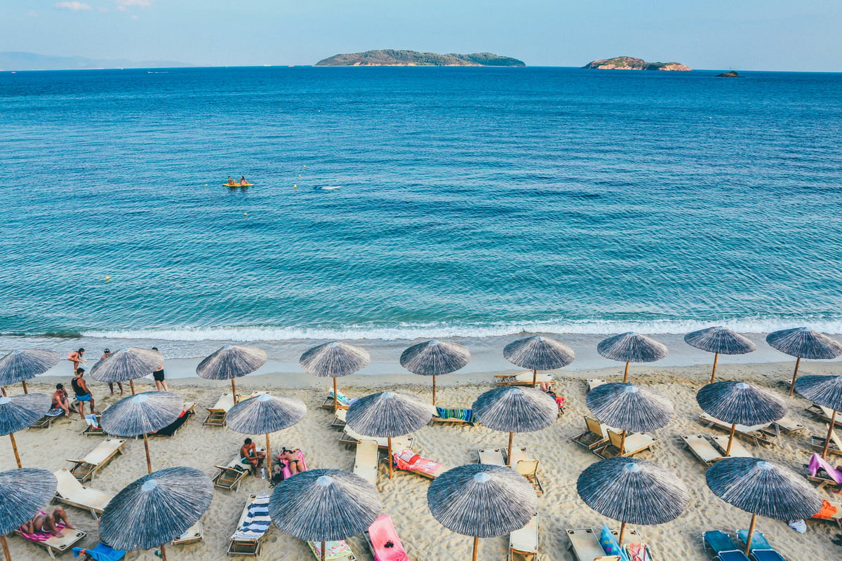 A Mykonos beach club or southern beach scene, turquoise water, loungers
