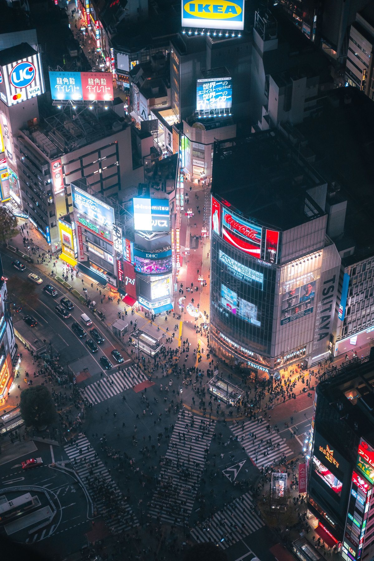 Aerial night view of the Shibuya Crossing scramble with neon billboards