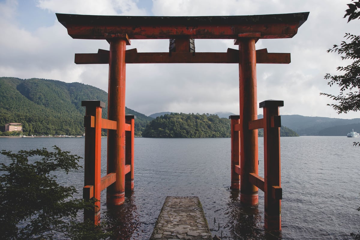 Hakone Shrine's red torii gate standing in Lake Ashi with mountains behind