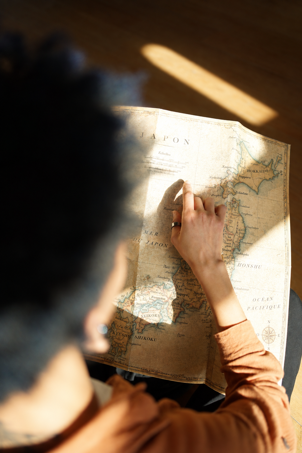 A hand tracing a route on a vintage map of Japan