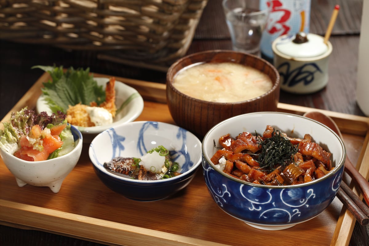 A variety of small Japanese dishes and rice served on a wooden tray
