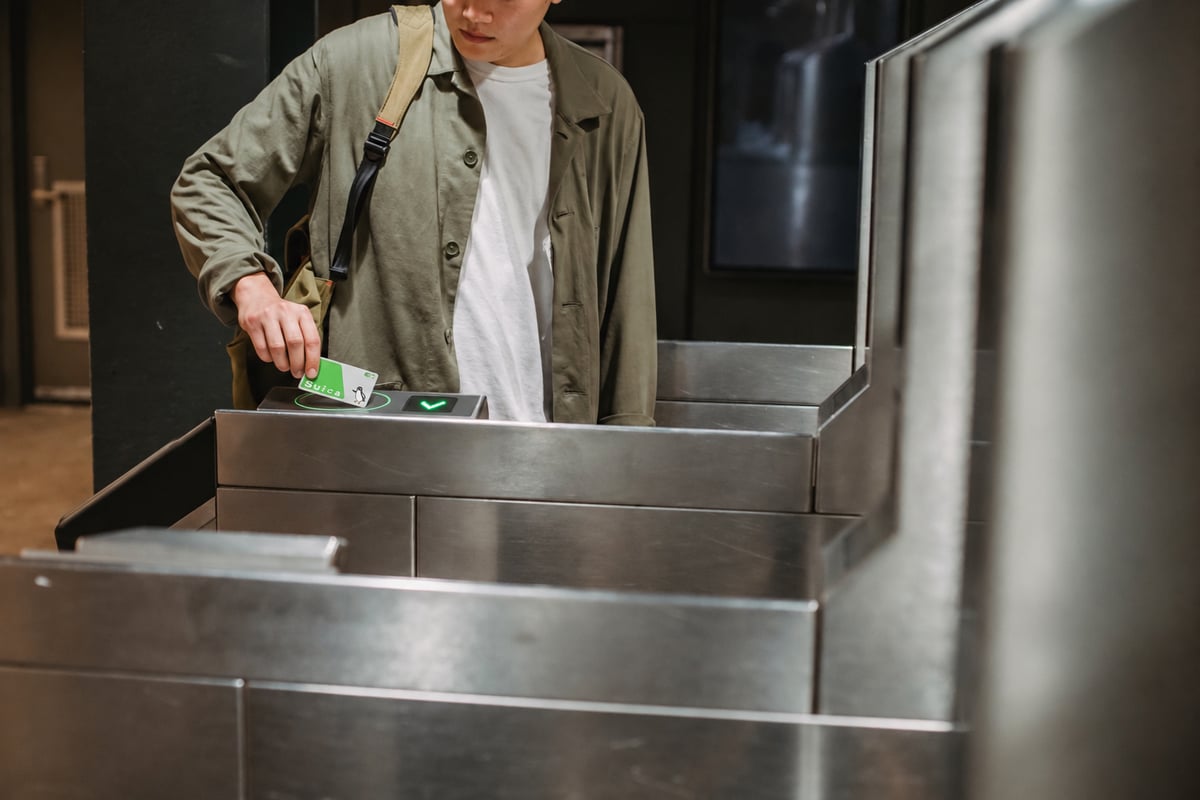 A hand tapping a Suica IC card on a station ticket gate reader