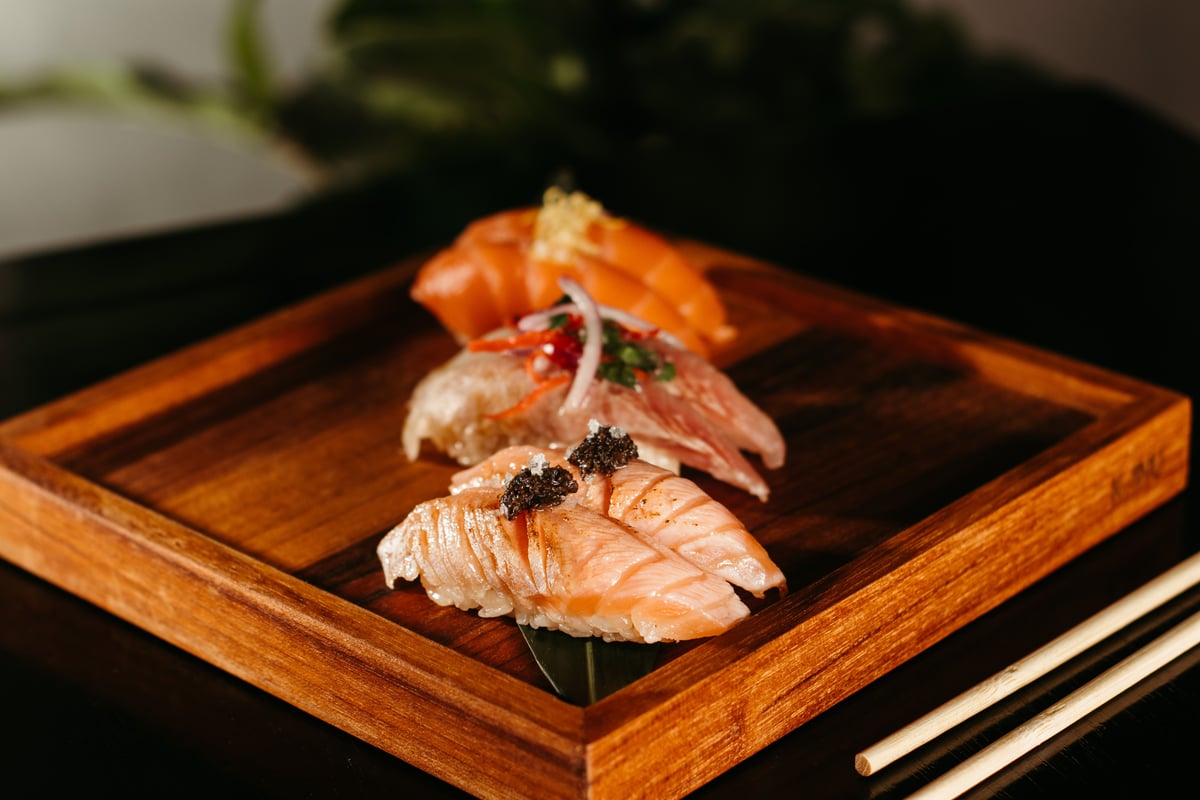An assortment of nigiri sushi on a wooden serving board