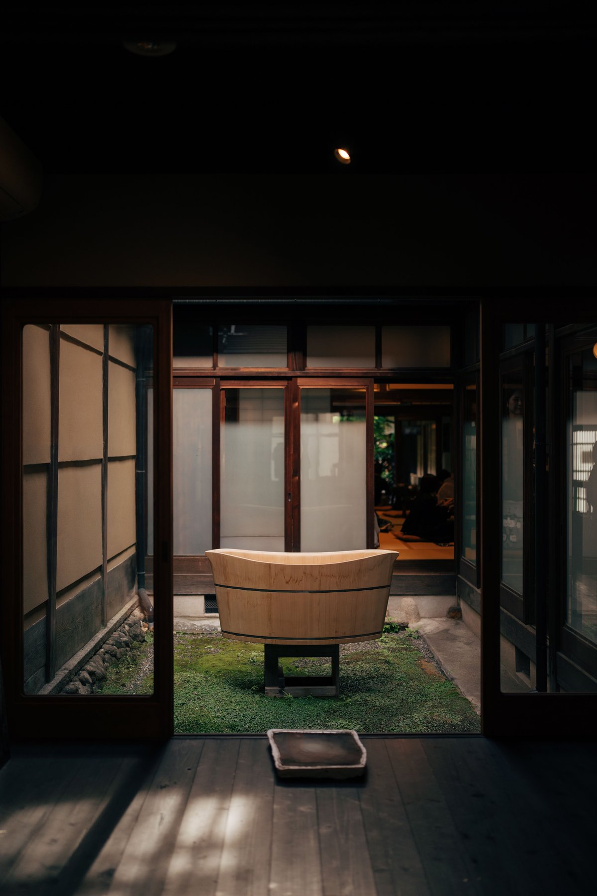 A private wooden hinoki soaking tub in a quiet ryokan courtyard